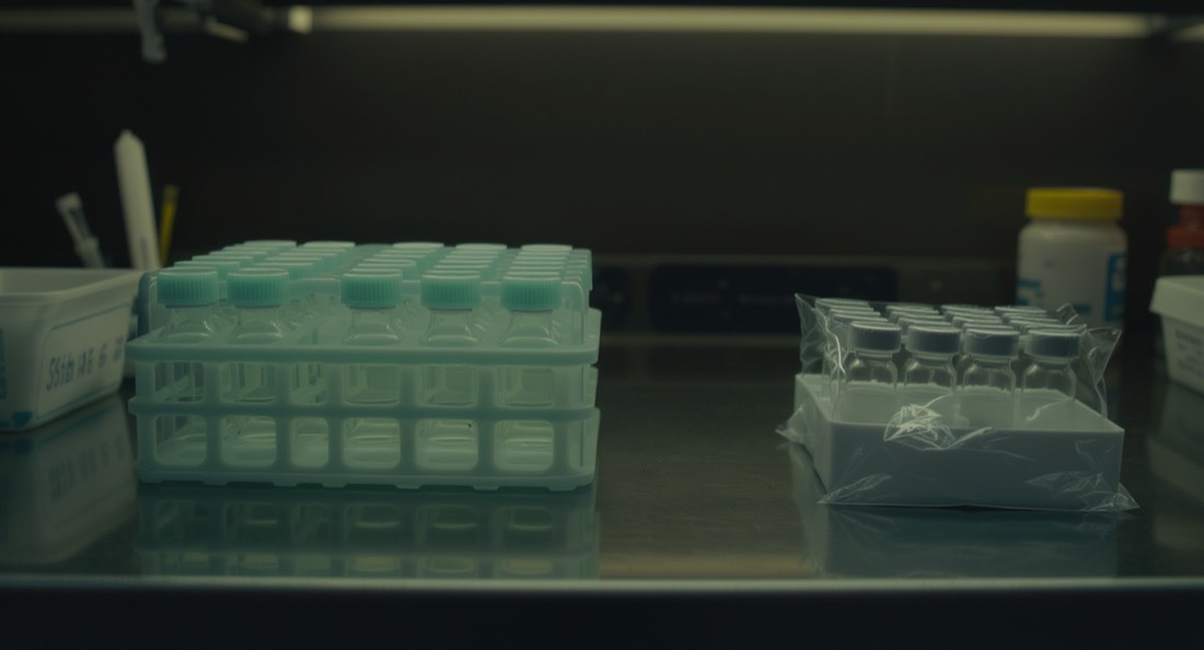 A sterile clinical preparation bench with unlabelled glass vials in a rack