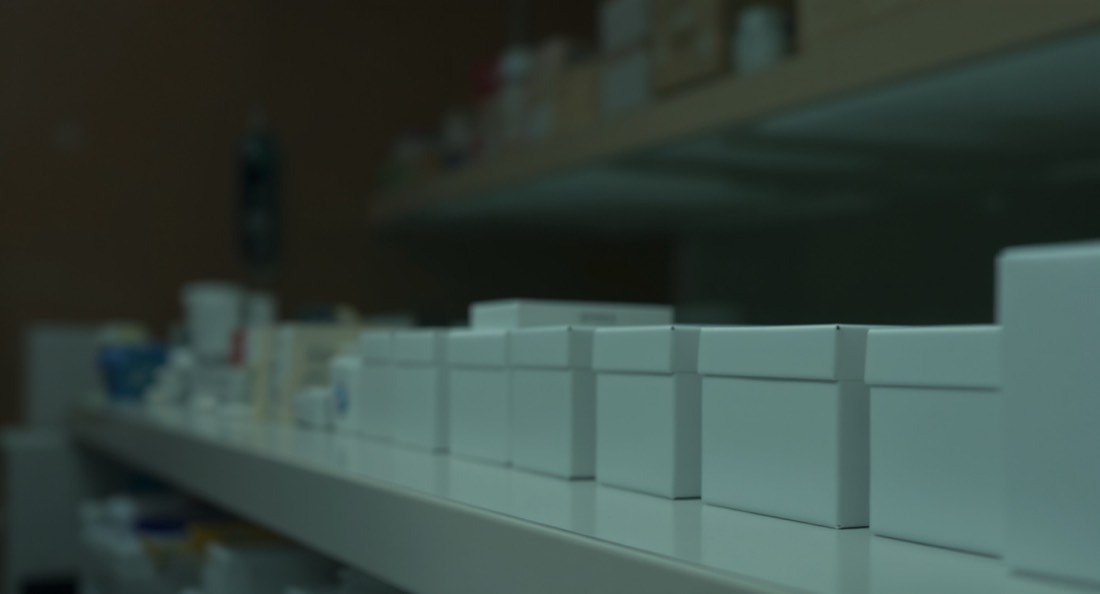 A pharmacy counter with rows of unlabelled boxes softly out of focus